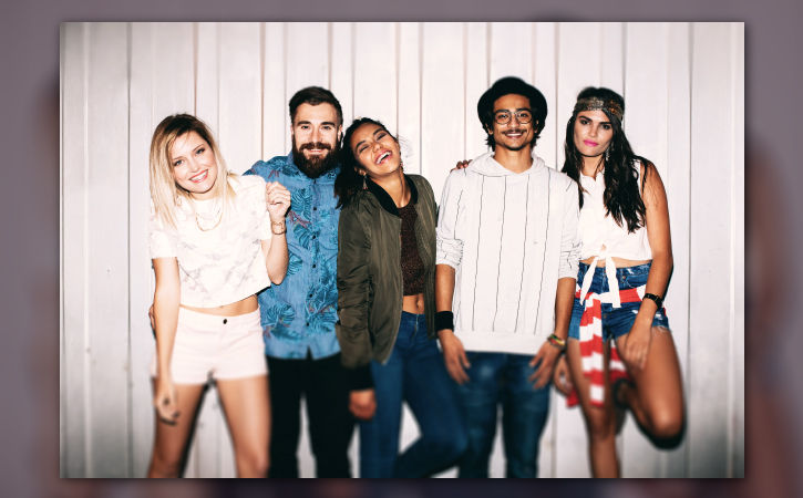 Edited image of three young ladies and two young men at a party has a warm tone with bottom and top edges blurred.