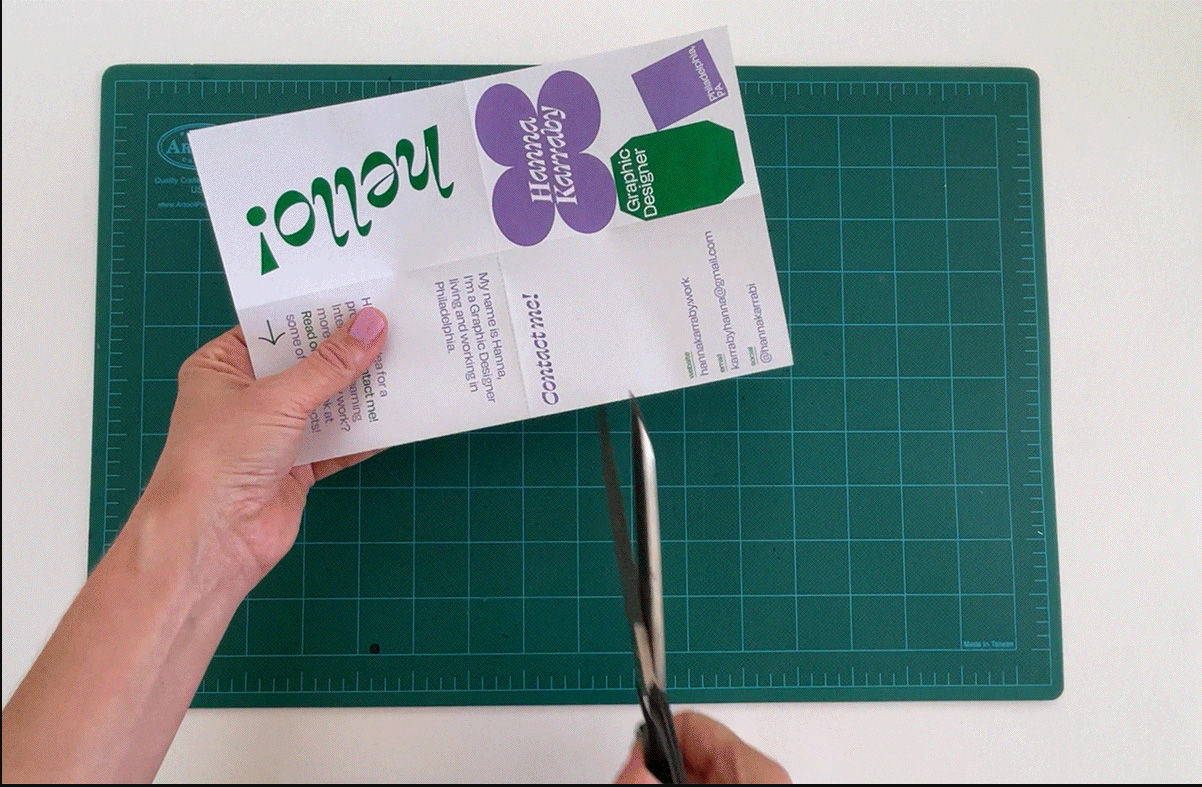 A person cutting a piece of paperDescription automatically generated