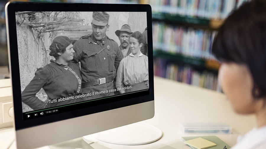 Student looks at a library computer monitor displaying an old photograph of a group of people