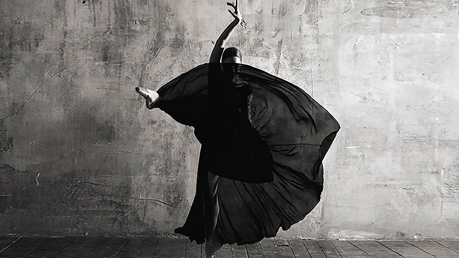 Black and white photograph of a dancer in a long dress striking a dramatic pose