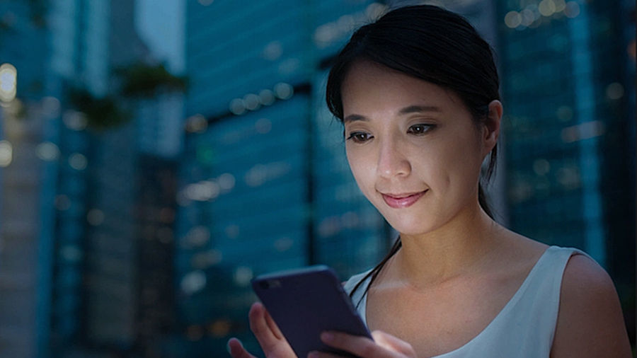 A woman's face lit up by the light from the phone she is looking into