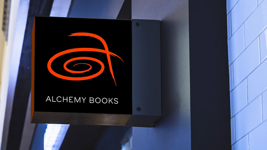 Outdoor digital sign shows a red stylized logo of the letter 'a' and store name 'Alchemy Books' underneath it