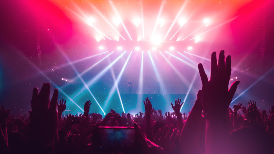 An image of a live music event with dramatic and colorful lighting effects