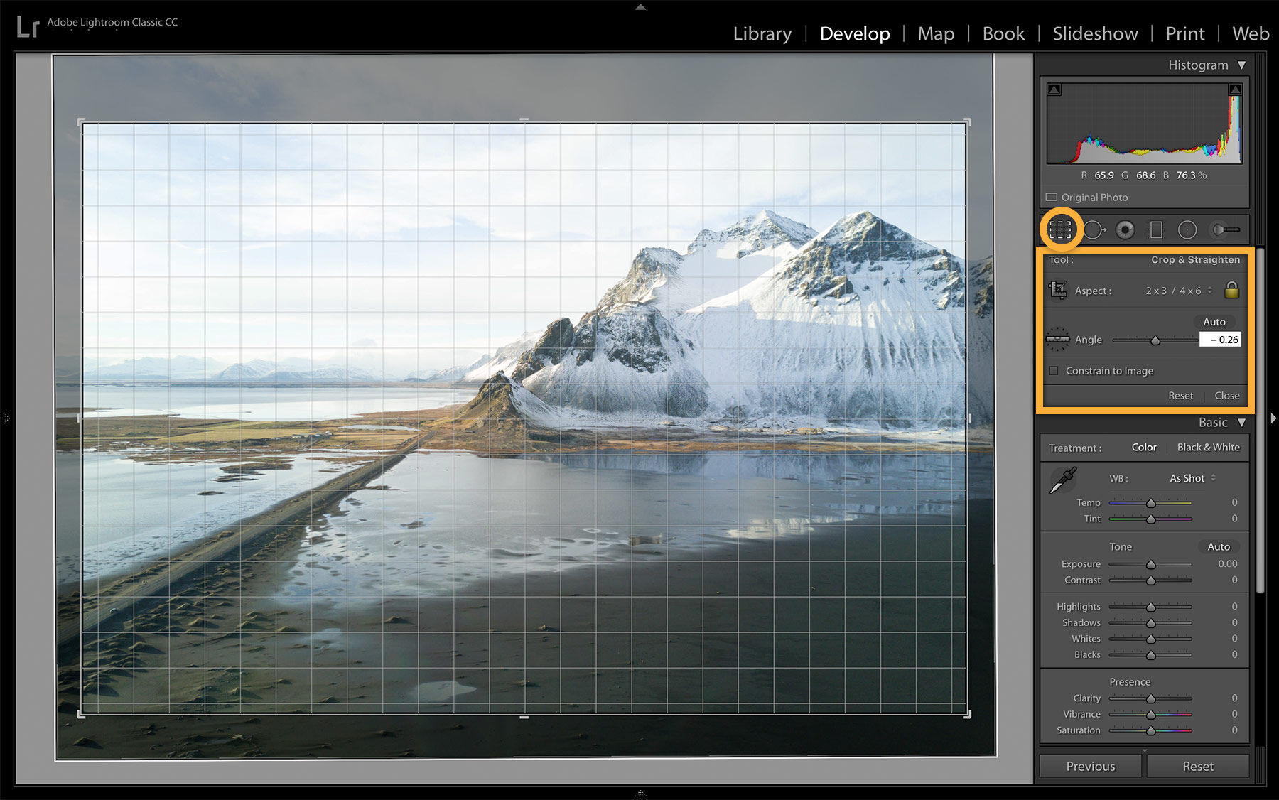 Arctic mountain range on a beach with white, cloudy sky is cropped and straightened to draw the viewer’s eye to a focal point