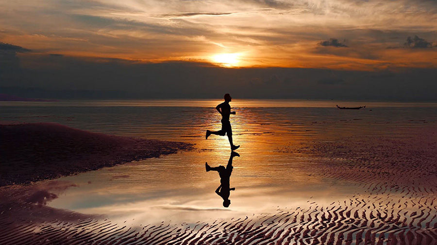 The color corrected video of the man jogging on the beach is ready for sharing on social media.