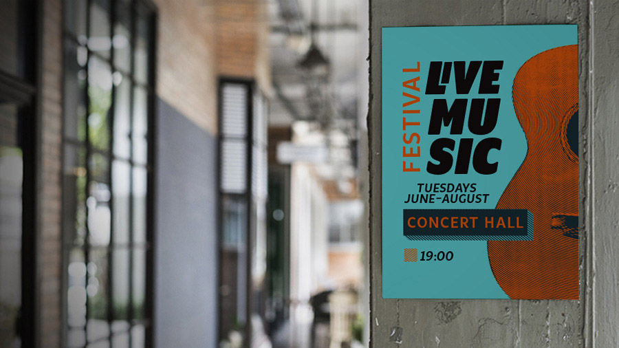Music festival poster hangs on a wooden post by a sidewalk lined with shops.