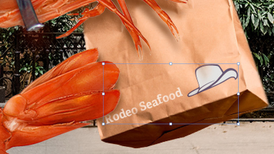 Close-up of brand logo being placed on brown bag with overlapping shrimp tail.