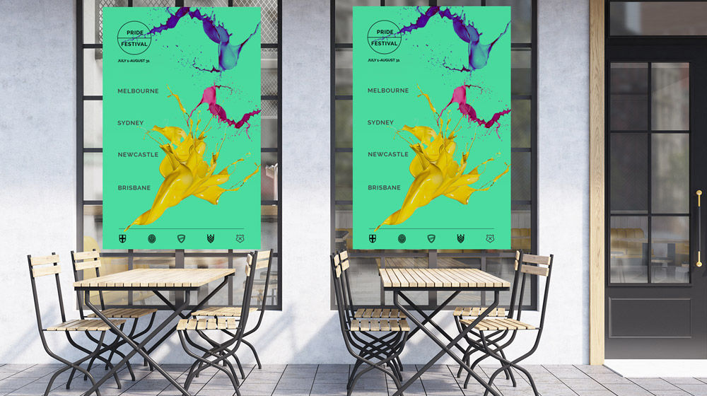 Sea green posters with Australian city names and purple, pink, and yellow paint splashes hang on windows in an outdoor café