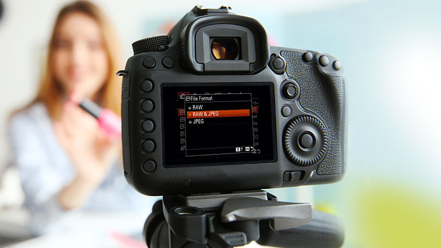 Back of a DSLR camera with Raw & JPEG settings selected with a woman in the background
