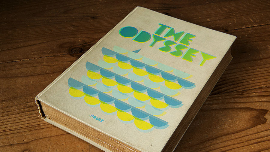 Homer’s book “The Odyssey” features a 1970’s style cover with blue, green, and yellow geometric shapes.