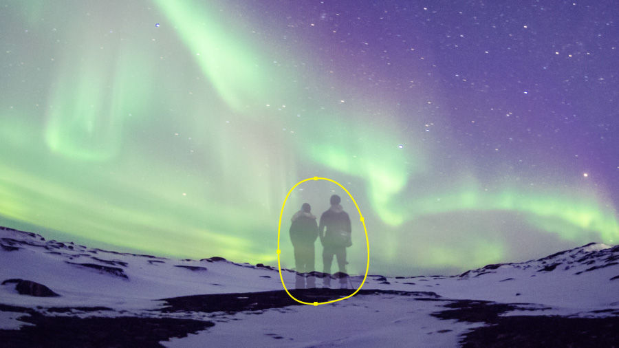 An image of people being edited out of a video of a snowy landscape under the aurora borealis