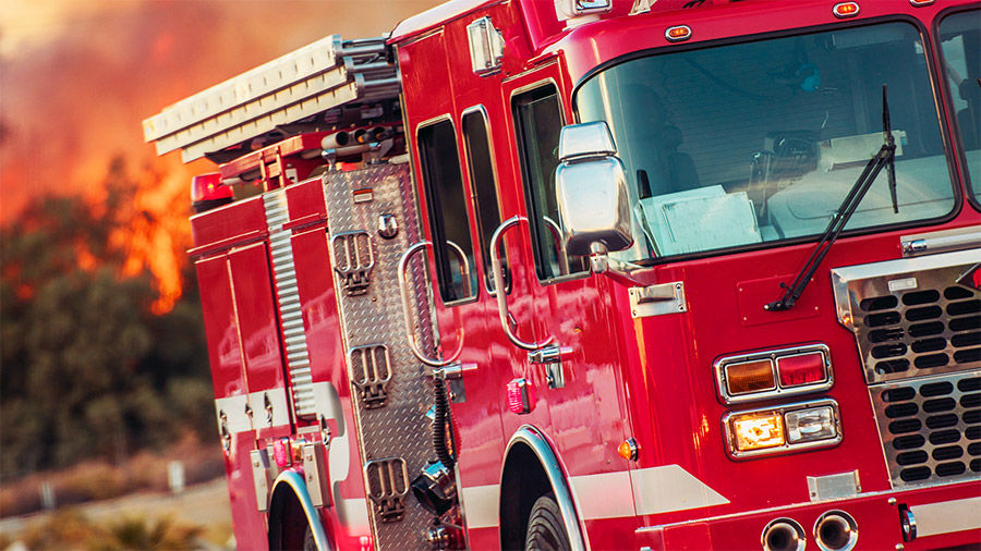 Photograph of a firetruck with a wildfire in the background