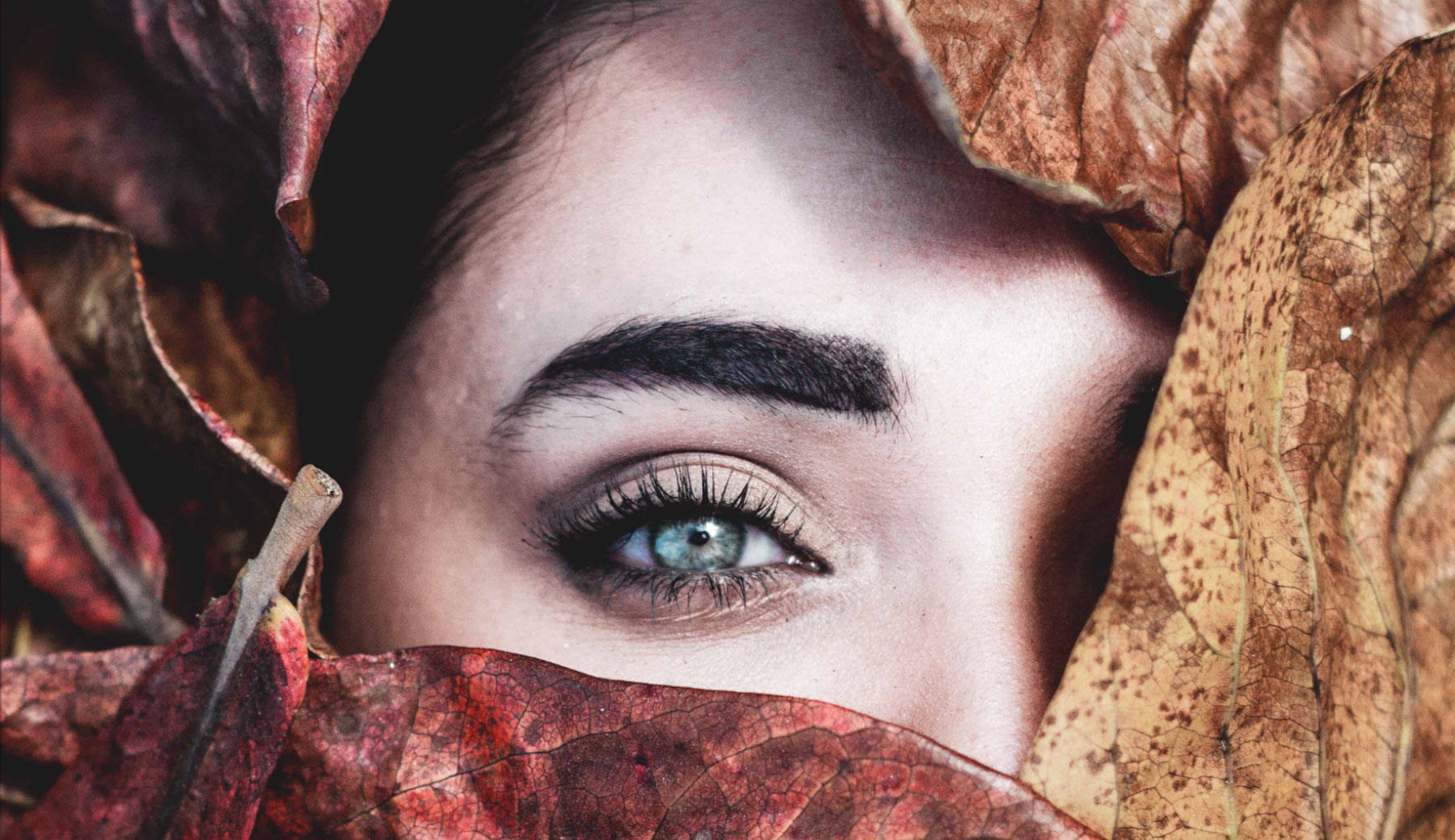 Woman's face covered with leaves.