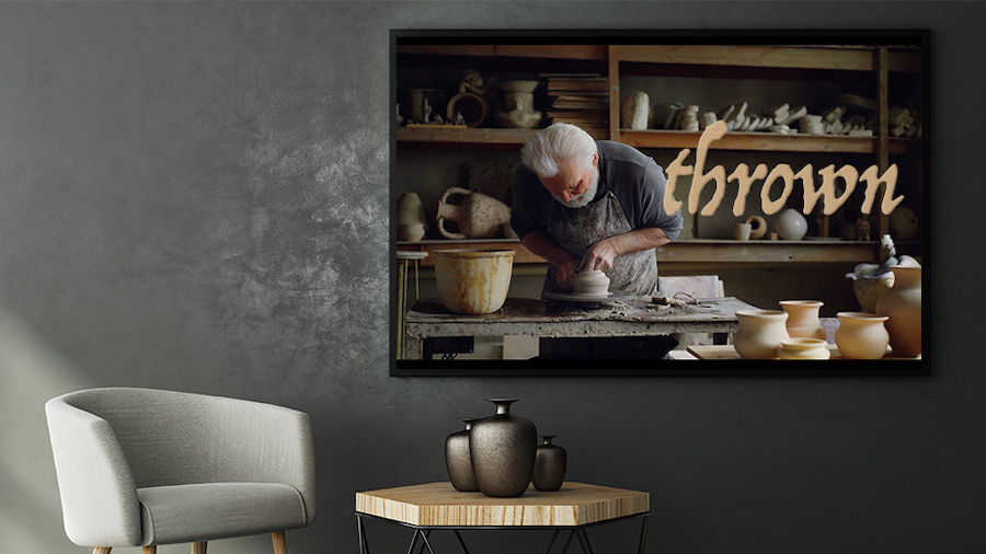 Wall-mounted monitor next to chair and coffee table displays a TV show called “thrown” and a potter at work