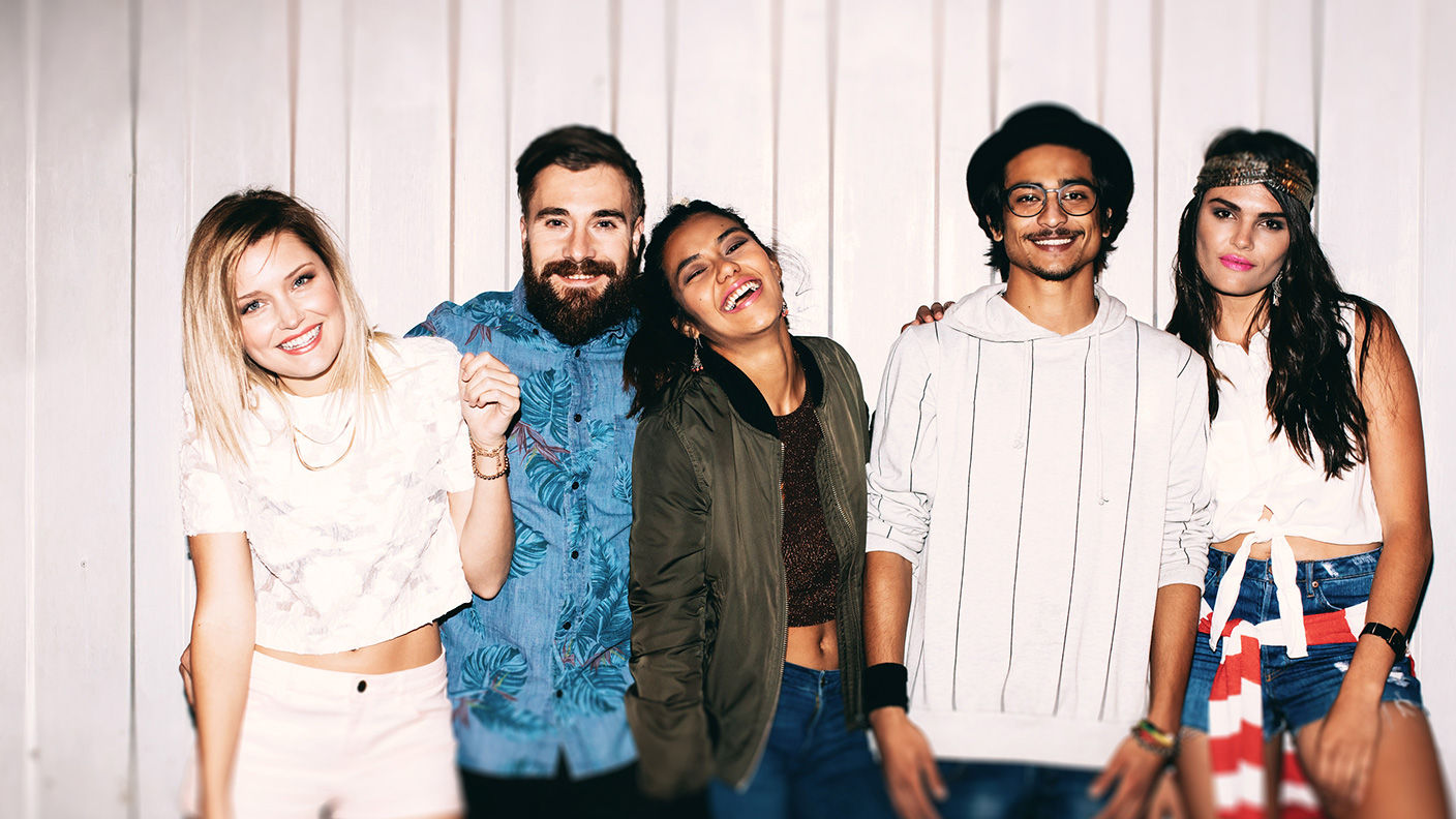 Three young ladies and two young men stand together at a party.