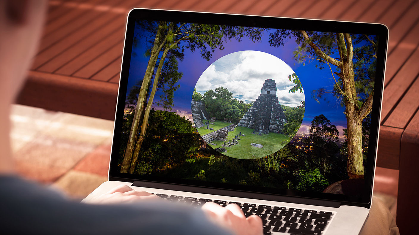 Laptop displaying a desktop image of an ancient ruin surrounded by trees