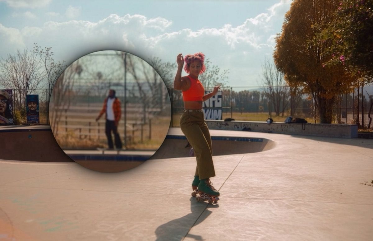 Una vista circular de aumento amplía a una persona que está en el fondo mientras un patinador se mueve por un parque de patinaje.