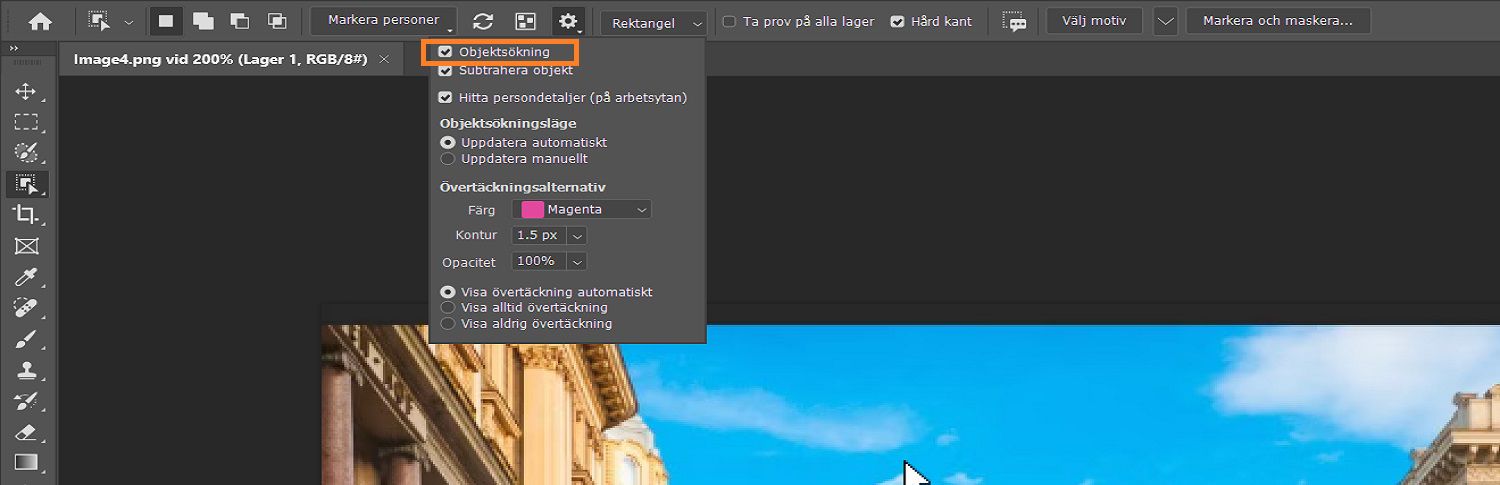 Objektsökaren är markerad i inställningsmenyn för Objektmarkering i options-fältet, ovanför en bild på byggnader på Photoshop-arbetsytan.
