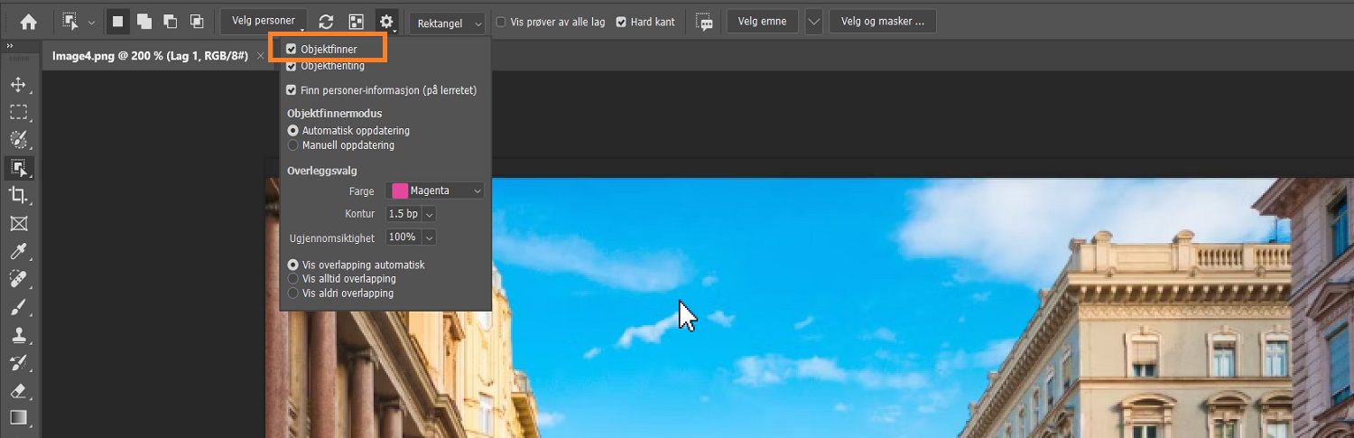 Objektfinner er fremhevet i innstillingsmenyen til Objektvalgverktøy i options-linjen, over et bilde av bygninger på Photoshop-lerretet.