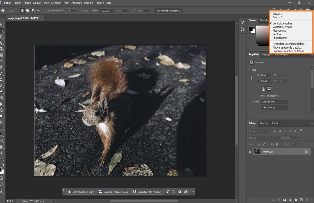 Interface de Photoshop affichant le menu déroulant Choisir un espace de travail avec des options comme Les indispensables, Photographie et des espaces de travail personnalisés.