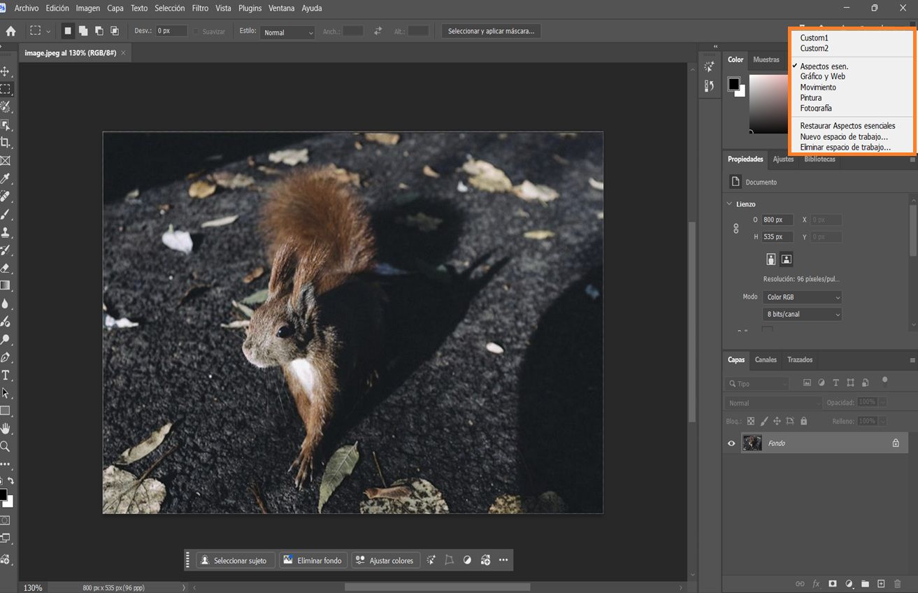Interfaz de Photoshop mostrando el menú desplegable Elegir un espacio de trabajo con options como Esenciales, Fotografía y espacios de trabajo personalizados.
