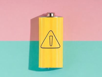 De afbeelding toont een gele batterij met een waarschuwingssymbool tegen een tweekleurige achtergrond, die half roze en groen is. Dit is een voorbeeld van een uitvoer nadat een stijlreferentieafbeelding is gebruikt.