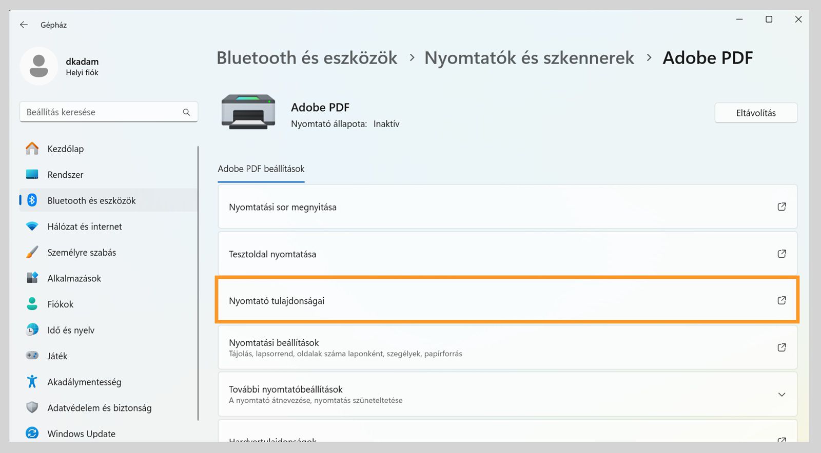 A Windows 11 Beállítások ablak az Adobe PDF nyomtató beállításait mutatja, például a Nyomtatási sor megnyitása, Nyomtató tulajdonságai, Nyomtatási beállítások és egyebek.