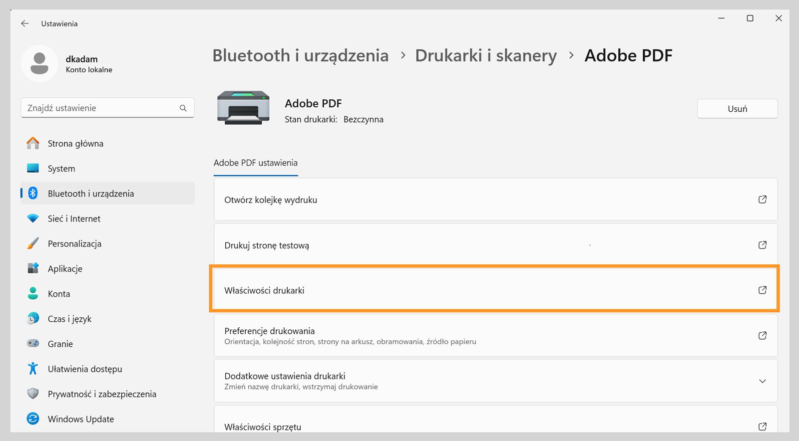 Okno Ustawienia systemu Windows 11 pokazuje ustawienia drukarki Adobe PDF, takie jak Otwórz kolejkę wydruku, Właściwości drukarki, Preferencje drukowania i inne. 