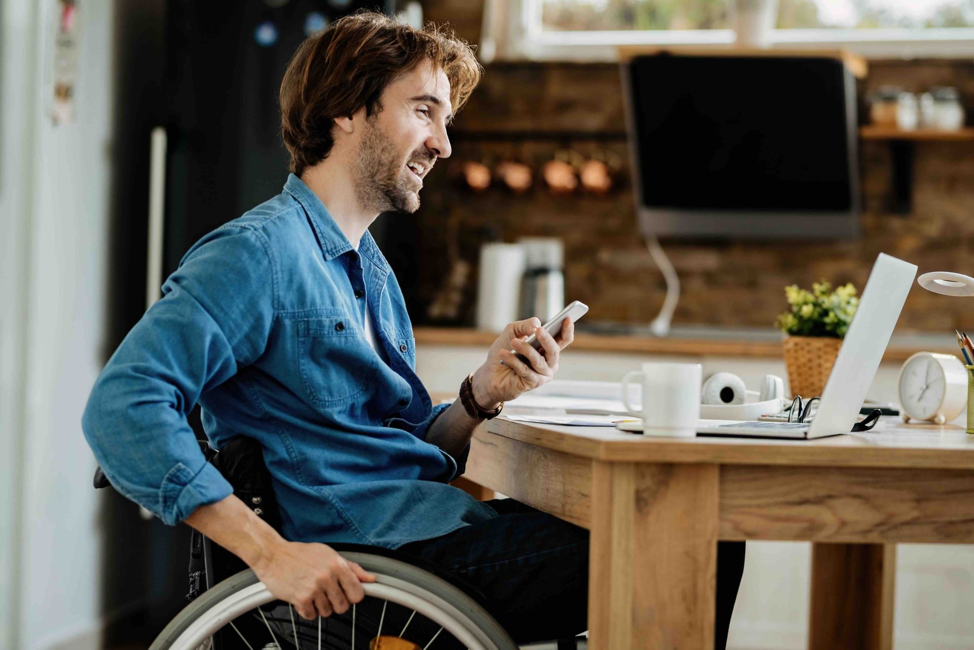 Un homme travaillant sur un bureau à domicile, avec un smartphone et un ordinateur portable.