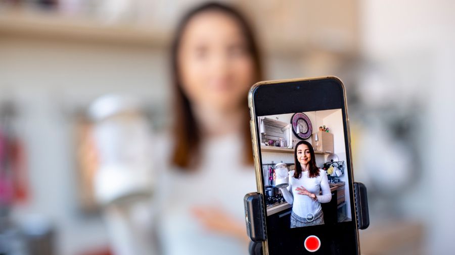 A content creator filming themselves on their iPhone creating social media content