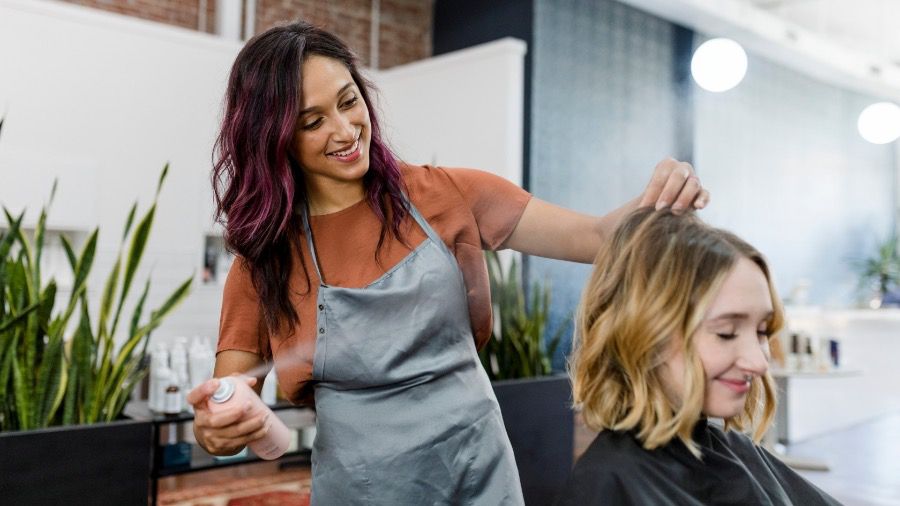 A business small business owner and hair stylist working with a client