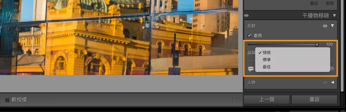 相片編輯軟體介面的螢幕擷圖，顯示反射在玻璃窗中的城市。反射顯示帶有柵欄和拱門的黃與橘建築物。右側的「干擾物移除」面板已勾選「反射」，品質設定為 100，並有「預覽」、「標準」和「最佳」選項。標為「上一頁」和「重設」的按鈕位於面板下方。